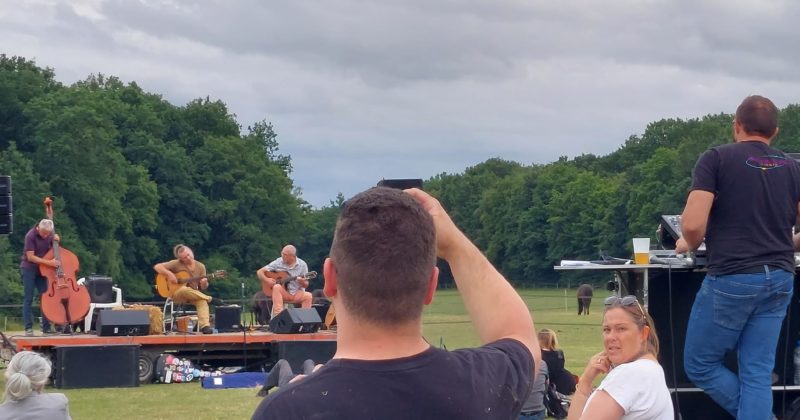 Concert en plein air avec musiciens sur scène et équipes de Symbiose Organisation assurant l'équipement sonore et éclairage.