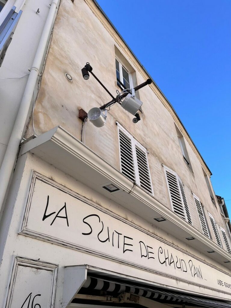 Éclairage et matériel sonore installés sur un mur extérieur d'un bâtiment, avec ciel bleu en arrière-plan.